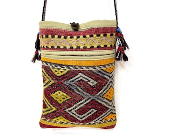 Può includere: Borsa a tracolla rettangolare in tessuto con motivo geometrico rosso, giallo, nero e grigio. La borsa ha una parte superiore beige con chiusura a bottone e una tasca con cerniera. Nappe e una tracolla completano il design.