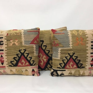 May include: Three decorative throw pillows with a traditional Turkish kilim pattern. The pillows are woven with a variety of colors, including red, black, beige, and brown.