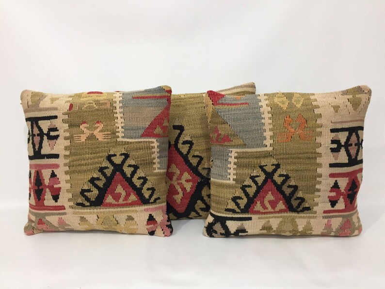 May include: Three decorative throw pillows with a traditional Turkish kilim pattern. The pillows are woven with a variety of colors, including red, black, beige, and brown.