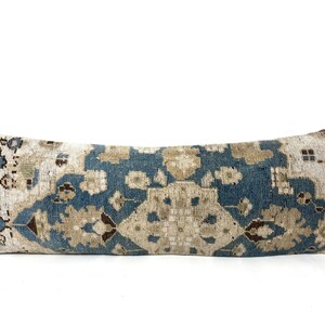 Könnte beinhalten: Ein langes, rechteckiges Kissen mit einem blauen und beigefarbenen Musterstoff. Das Muster ist ein traditionelles persisches Design mit komplizierten Details.
