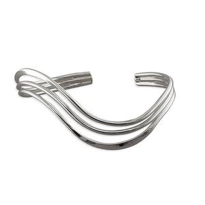 Könnte beinhalten: Ein silbernes Armreif-Armband mit drei wellenförmigen Bändern.