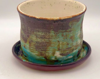 May include: A ceramic planter with a brown, green and blue glaze. The planter has a matching saucer.