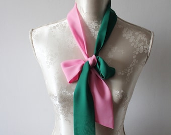 May include: A pink and green scarf tied in a bow on a white mannequin.