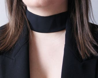 Könnte beinhalten: Eine Frau trägt einen schwarzen Blazer mit einer schwarzen Choker-Kette.