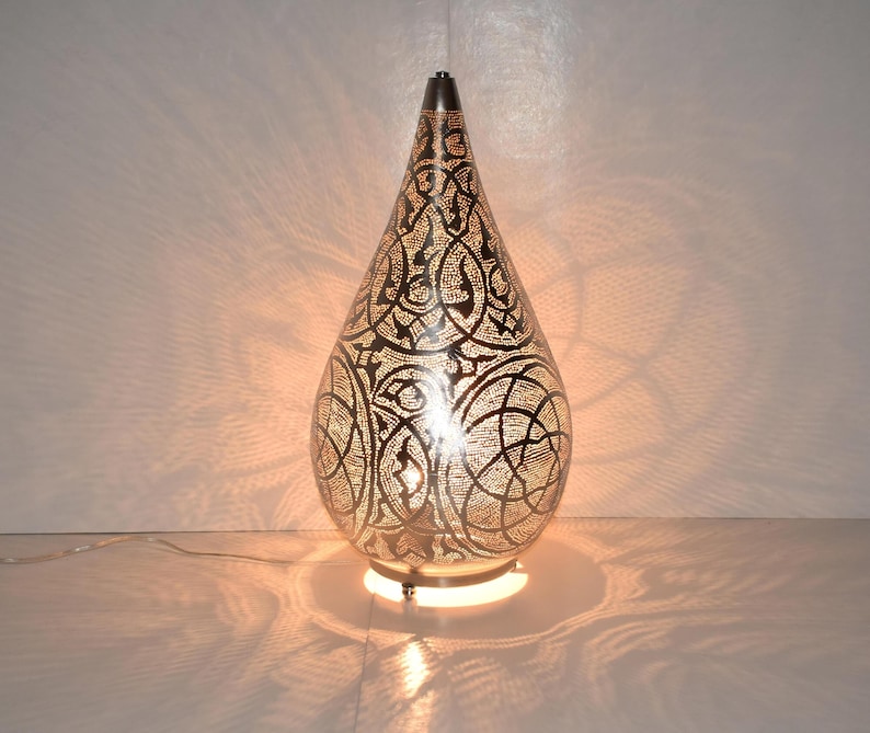 Handmade Moroccan brass gourd lamp with intricate cutouts, glowing warmly as a floor or bedside lamp. Perfect as a lantern-style centerpiece or decorative table light for boho, rustic, or eclectic interiors.