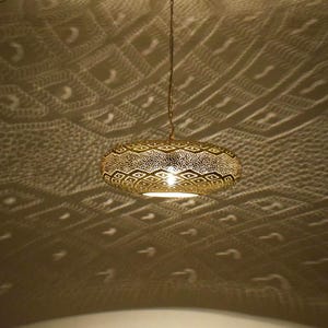 May include: A gold-colored, oval-shaped pendant light fixture with intricate cut-out patterns. The light casts a decorative pattern on the ceiling. The fixture hangs from a chain, illuminating the room with a warm glow. This decorative lighting fixture adds a touch of elegance.