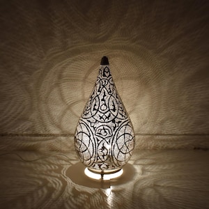 Moroccan brass table lamp shaped like a gourd with hand-punched patterns. Functions as a glowing lantern centerpiece, floor lamp, or bedside light for cozy, atmospheric spaces.