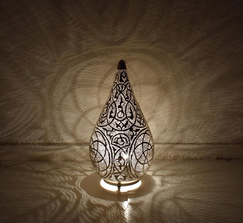 Moroccan brass table lamp shaped like a gourd with hand-punched patterns. Functions as a glowing lantern centerpiece, floor lamp, or bedside light for cozy, atmospheric spaces.