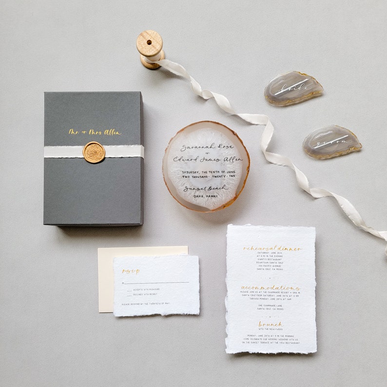 Black whimsical modern calligraphy wedding invitation on a white & tan agate slice, charcoal gray box, gold wax seal and cream hand-dyed silk ribbon with handmade paper details card, rsvp card with gold spot calligraphy, two bride groom place cards