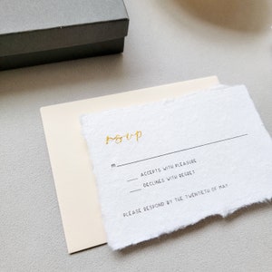 Rsvp card with blush light pink 4bar envelope, gold spot hand calligraphy in gold ink, pointed pen on fluffy deckled edge handmade cotton paper with box in the background
