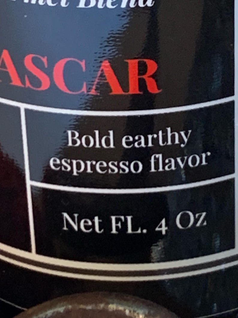 May include: Black and white label with red text that reads "ASCAR" and the words "Bold earthy espresso flavor" and "Net FL. 4 Oz".