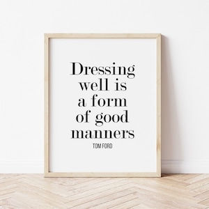 May include: A framed print with the quote "Dressing well is a form of good manners" by Tom Ford in black text on a white background. The frame is a light wood color.