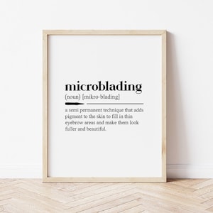 以下が含まれることがあります： 白い背景に黒い文字で「microblading」の定義が書かれた額入りのプリント。定義では、マイクロブレーディングを眉毛を埋める半永久的な技術と説明しています。フレームは明るい木の色です。