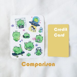 May include: A white sticker sheet featuring various green alien illustrations with different expressions and activities. One alien is in a spaceship, another is skateboarding, and one is wearing headphones. The text "NOT GUILTY" is also present.