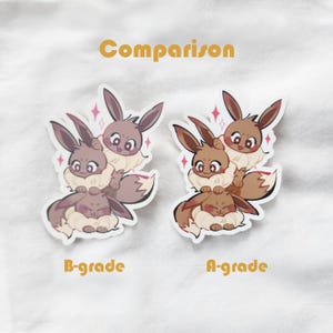 Puede incluir: Dos pegatinas con personajes de dibujos animados con orejas de conejo y pelaje esponjoso. Las pegatinas est&aacute;n etiquetadas como "B-grade" y "A-grade" y se comparan una al lado de la otra. La palabra "Comparison" est&aacute; escrita en naranja encima.