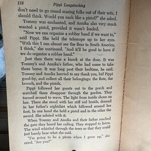 Może przedstawiać: Otwarta strona książki z tekstem z "Pippi Pończoszanki" Astrid Lindgren. Tekst jest czarnym tuszem na postarzanym, kremowym papierze. Dwie czarne metalowe podp&oacute;rki do książek trzymają strony otwarte.