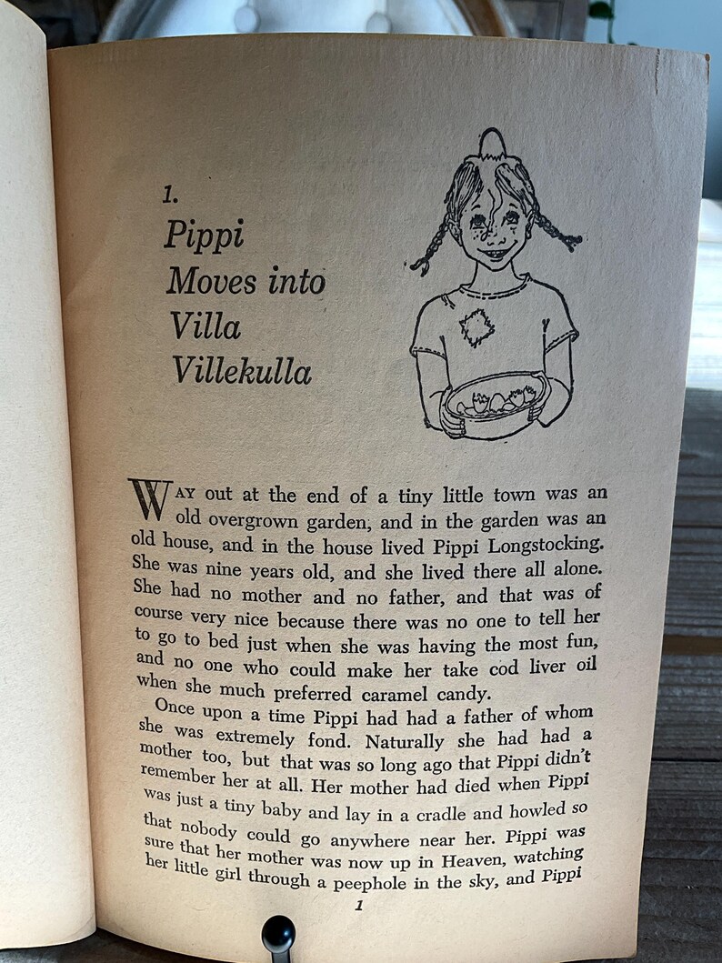 Może przedstawiać: Otwarta strona książki z tekstem i czarno-białą ilustracją dziewczynki z warkoczami. Tekst brzmi "Pippi wprowadza się do Villa Villekulla".