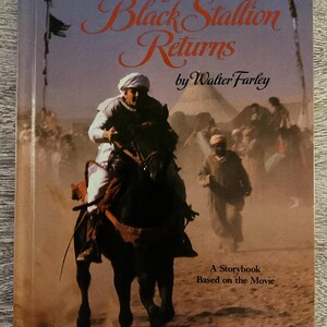 May include: The cover of "The Black Stallion Returns" by Walter Farley. It depicts a man riding a black horse in a desert scene. The title is in orange script, and the subtitle reads "A Storybook Based on the Movie."