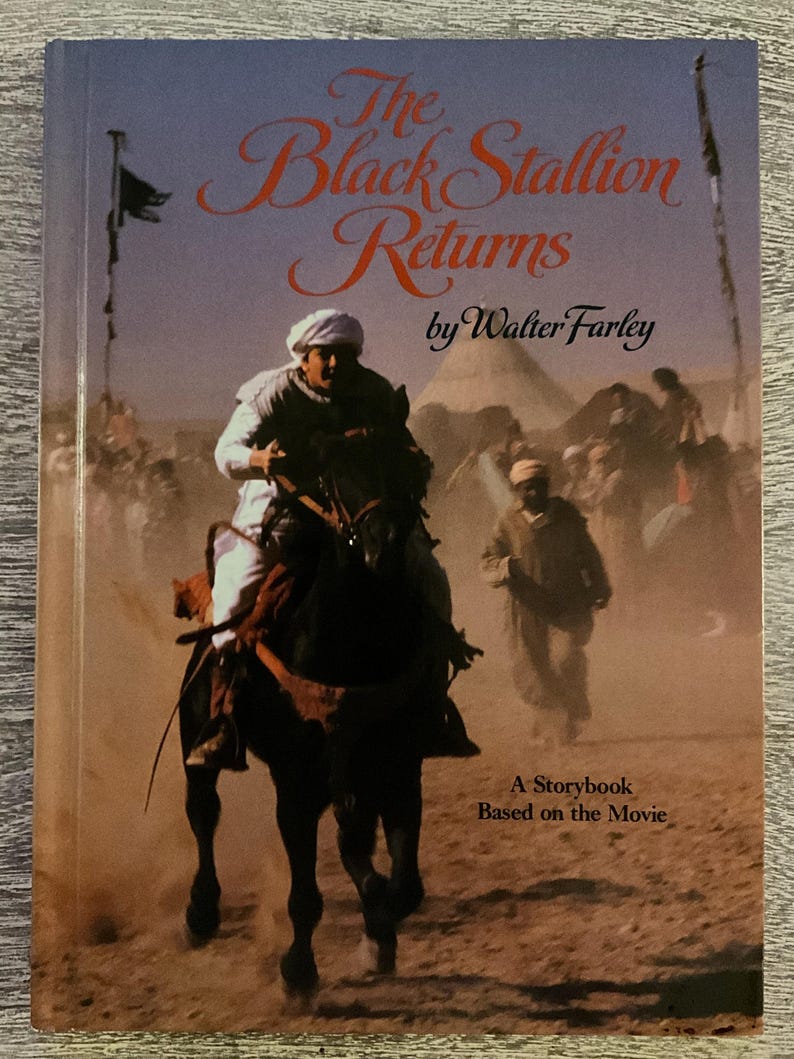 May include: The cover of "The Black Stallion Returns" by Walter Farley. It depicts a man riding a black horse in a desert scene. The title is in orange script, and the subtitle reads "A Storybook Based on the Movie."