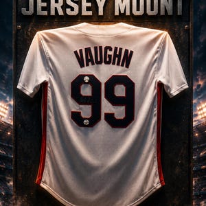 May include: A baseball jersey mount featuring a white jersey with the name "VAUGHN" and the number "99" in black. The jersey has red accents and is displayed on a textured metal background. The text "BASEBALL JERSEY MOUNT" is at the top.