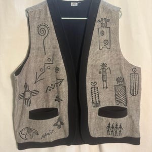 May include: A sleeveless vest in a heathered gray fabric with black trim and two front pockets. The vest features black embroidered line art designs including spirals, arrows, geometric shapes, and stylized figures across the front panels.