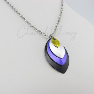 May include: A silver chain necklace with a layered pendant. The pendant is made of three overlapping oval shapes in black, purple, silver, and gold.