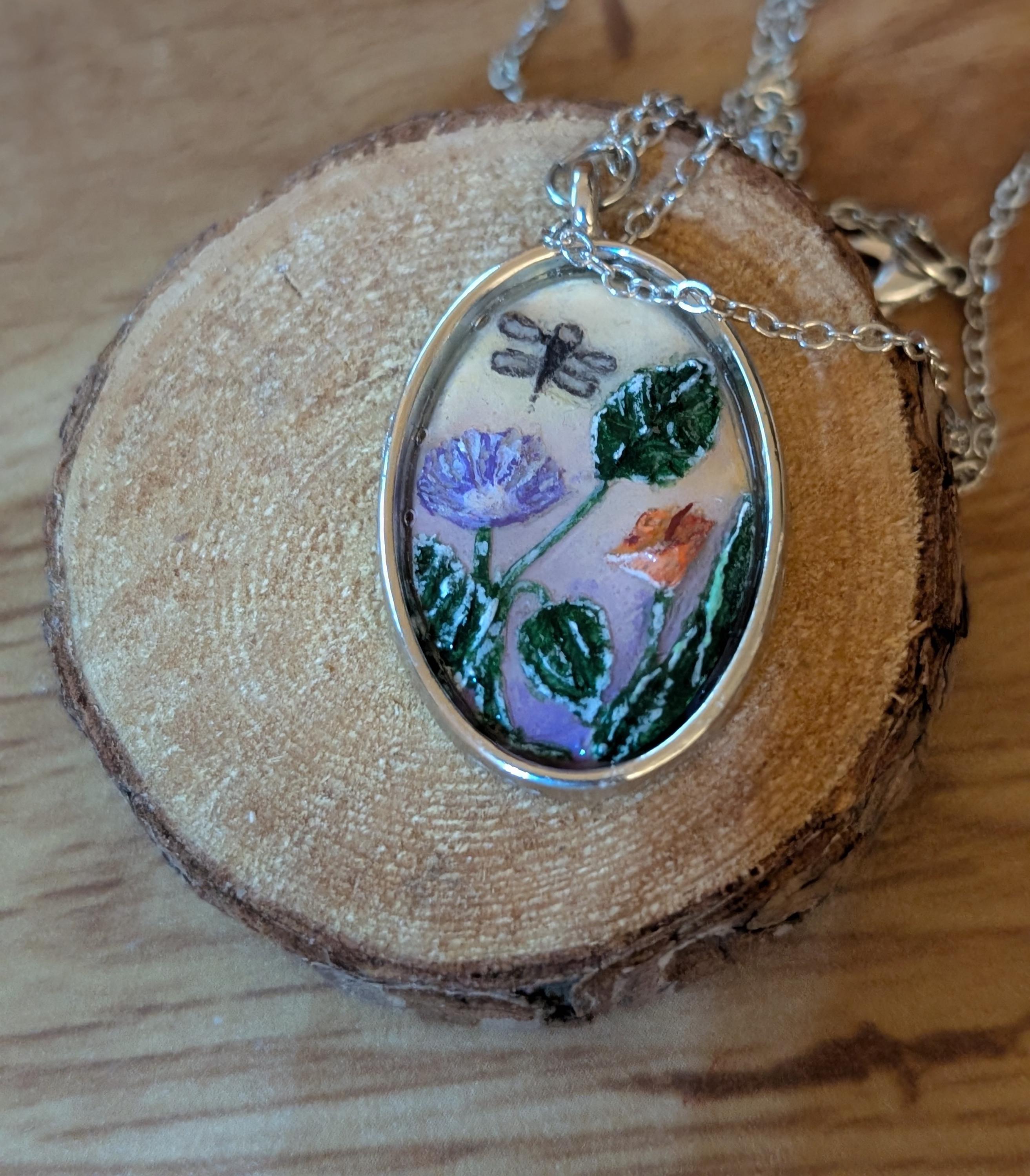 Les Fleurs: Hand-carved and painted clay and resin pendant. Handmade jewelry. Flowers, leaves, and a dragonfly make up this beautiful scene.