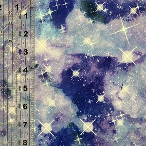Puede incluir: Tela con un dise&ntilde;o celestial que presenta un fondo de acuarela azul oscuro y p&uacute;rpura. Estallidos de estrellas blancas y brillantes y diminutos puntos blancos est&aacute;n dispersos por la tela. Una regla est&aacute; en el lado izquierdo.