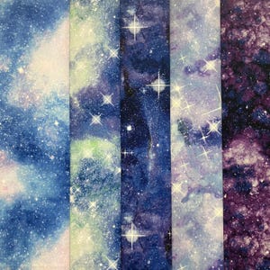 Puede incluir: Muestras de tela con un dise&ntilde;o de galaxia. La tela tiene un efecto de acuarela con tonos de azul, morado y blanco, y est&aacute; salpicada de formas blancas en forma de estrella. Las muestras est&aacute;n dispuestas verticalmente.