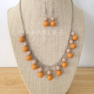 May include: A silver chain necklace with a double row of orange and beige round beads. Matching earrings with the same beads are included.