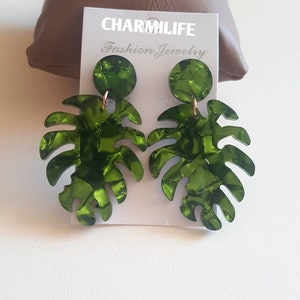 May include: Green monstera leaf earrings with a gold accent. The earrings are on a white card with the text "CHARMLIFE Fashion Jewelry".