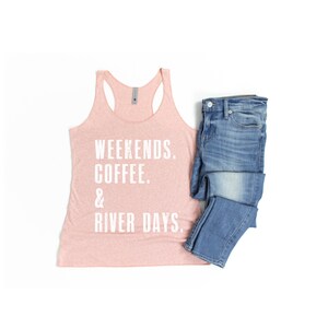 Puede incluir: Un top de tirantes rosa con el texto "Weekends. Coffee. & River Days." impreso en blanco. El top de tirantes se combina con unos vaqueros azules.