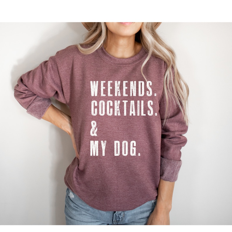 May include: A maroon sweatshirt with the text "Weekends. Cocktails. & My Dog." printed in white.
