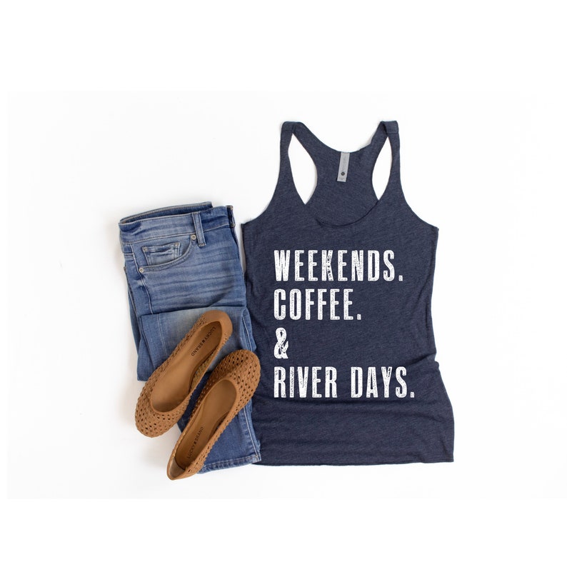 Puede incluir: Un top de tirantes azul marino con el texto "Weekends. Coffee. & River Days." impreso en blanco.