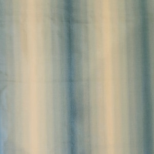 May include: A fabric with vertical stripes in shades of blue and cream. The stripes are soft and blurred, creating a watercolor effect. The fabric appears to be lightweight and suitable for various textile projects.