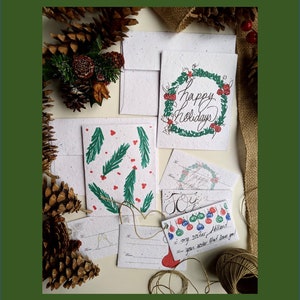 Deux graines de fleurs sauvages d'enveloppe de carte de Noël à planter, six étiquettes-cadeaux à planter, houx sur du papier de graine de fleurs sauvages blanc, joyeux Noël
