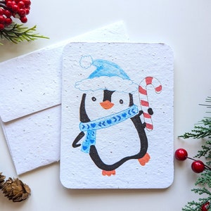 Pinguino invernale di Natale con canna da zucchero su carta piantabile o carta bianca per acquerello, bordi consumati