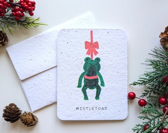 Funny Christmas pun card, Toad frog hagning from a bow on plantable paper or watercolor white paper, worn out borders