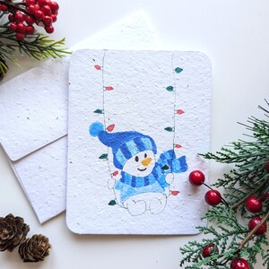 Bonhomme de neige sur la balançoire lumineuse de Noël sur du papier à planter ou du papier blanc aquarelle, bordures usées