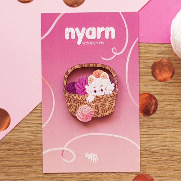 Nyarn • wooden pin of a basket with a white cat playing around with colorful balls of yarn