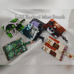 May include: A collection of colorful Ipod Earbud Mini Pouches. The pouches feature various patterns, including a green and white design, a tie-dye pattern, and a cartoon design. Each pouch has a small strap and a clasp.
