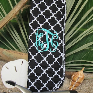 May include: Black and white patterned curling iron case with a teal monogram. The case is next to a curling iron, starfish, and seashells. The case has a white trim and a black and white quatrefoil pattern.