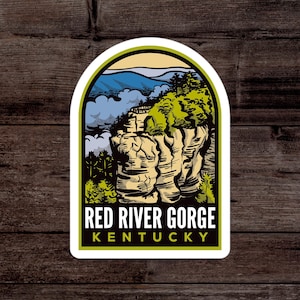 May include: A green, white, and yellow sticker with an illustration of a cliff overlooking a valley with mountains in the background. The text "RED RIVER GORGE KENTUCKY" is printed on the sticker.