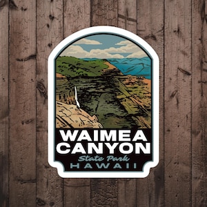 May include: A sticker featuring a scenic view of Waimea Canyon State Park in Hawaii. The sticker is white with a blue, green, and brown illustration of the canyon. The text "Waimea Canyon State Park Hawaii" is printed in black on the sticker.