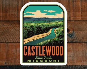 May include: A vintage-style sticker featuring a scenic view of a river winding through a forest, with a blue sky and white clouds in the background. The sticker reads "CASTLEWOOD State Park MISSOURI".