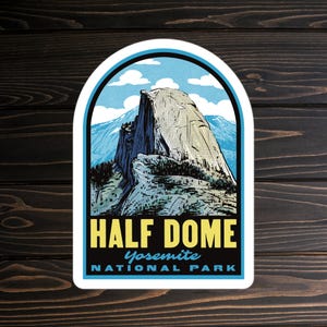 May include: A sticker featuring a vintage-style illustration of Half Dome in Yosemite National Park. The design includes a gray mountain, blue sky, and the text "HALF DOME Yosemite NATIONAL PARK" in yellow and blue.