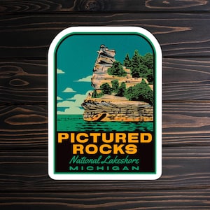 May include: A rectangular sticker featuring a scenic illustration of Pictured Rocks National Lakeshore in Michigan. The design includes a rock formation, trees, water, and the text "PICTURED ROCKS NATIONAL LAKESHORE MICHIGAN" in a retro style.