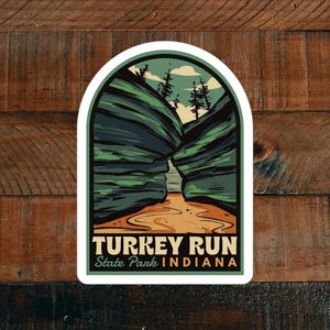 May include: A sticker featuring a scenic illustration of Turkey Run State Park in Indiana. The sticker shows a narrow canyon with a stream running through it, surrounded by lush green trees and cliffs. The text "TURKEY RUN State Park INDIANA" is printed in a vintage style font.