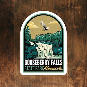 May include: A sticker featuring a vintage-style illustration of Gooseberry Falls State Park in Minnesota. The sticker shows a waterfall cascading down a rocky cliff, with lush green trees surrounding it. A bald eagle flies overhead against a yellow sky with clouds. The text "Gooseberry Falls State Park Minnesota" is printed below the image.