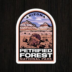May include: A sticker featuring a landscape of the Petrified Forest National Park in Arizona. The design includes a mountain range under a blue sky, petrified wood, and the text "Petrified Forest National Park."